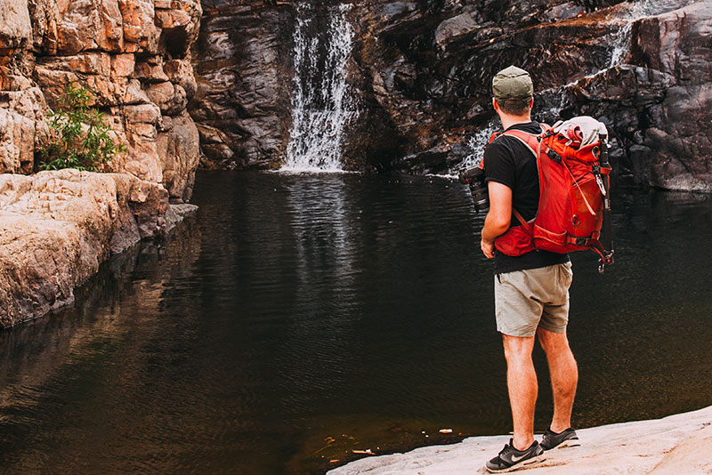 This is describe the adventure, in this a men stand in front of water fall.